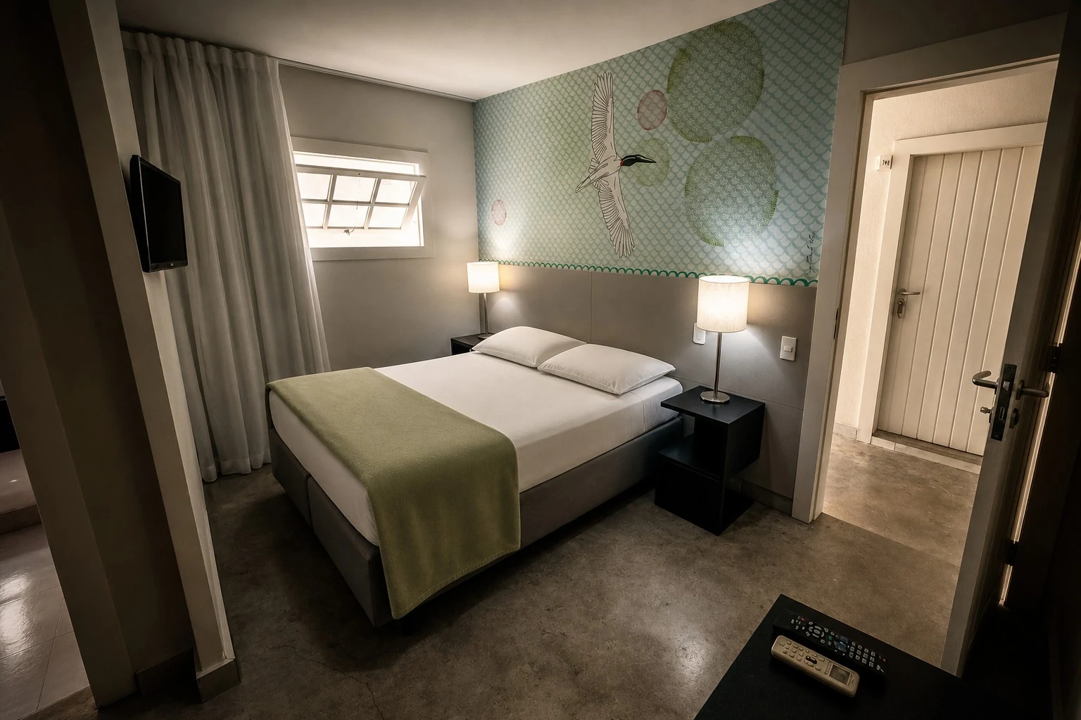 Quarto Standard com cama de casal, painel de parede e janela alta