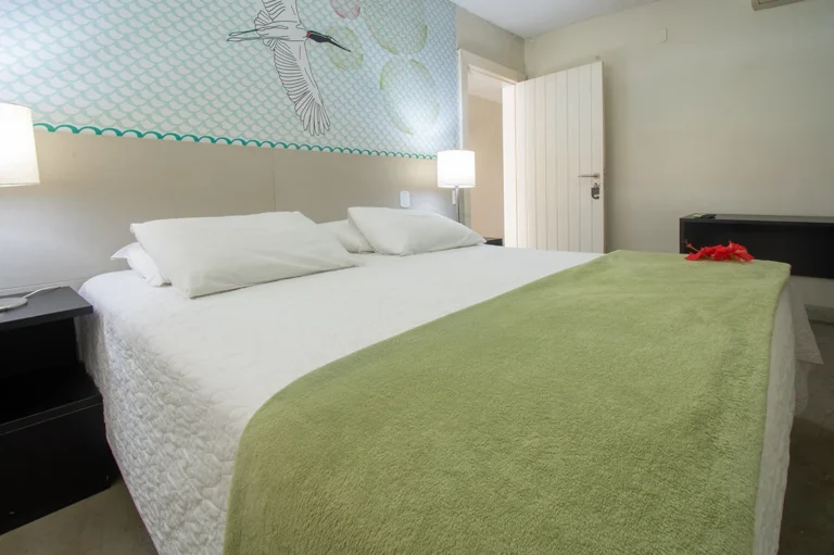 Cama de casal da Suíte Standard, com painel de parede e abajures
