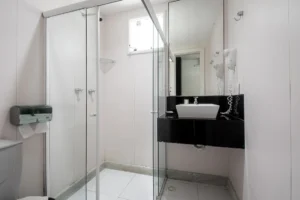 Banheiro da Suíte Standard, com box de vidro e bancada preta