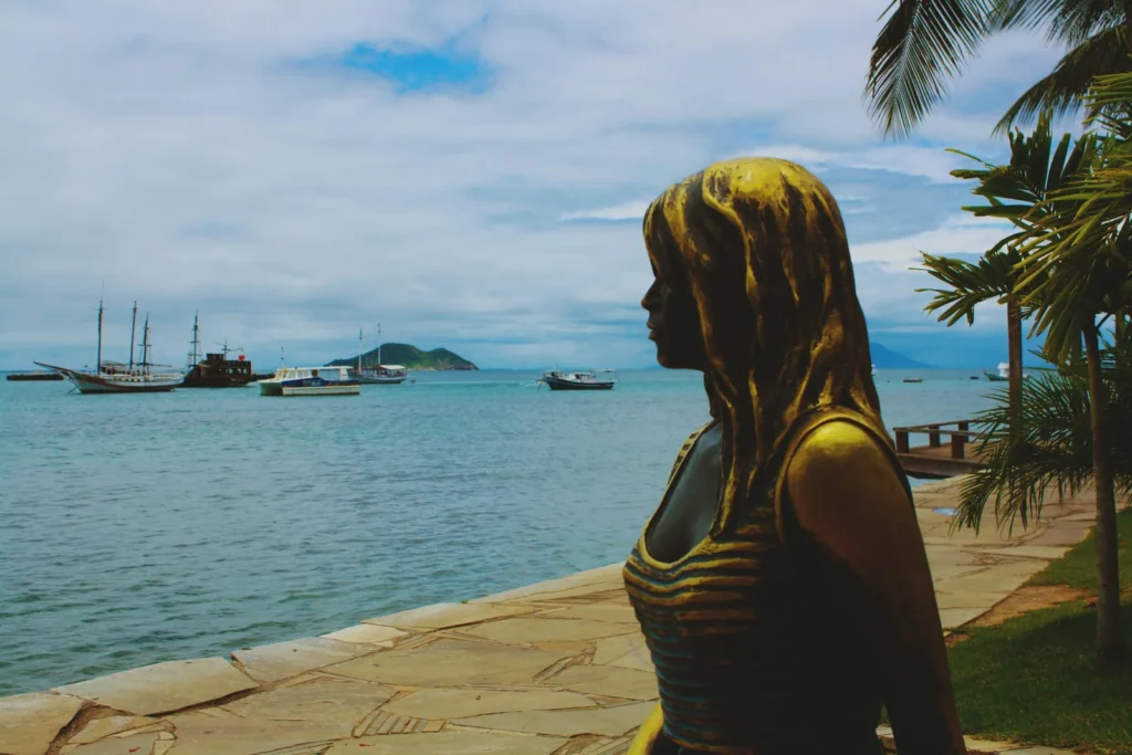 Estátua de Brigitte Bardot na Orla Bardot, com escunas na enseada