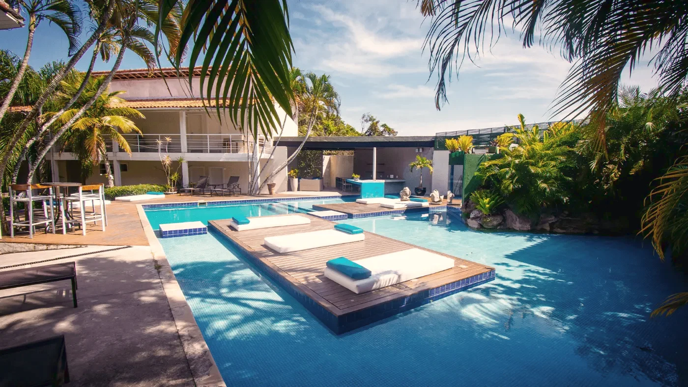 Piscina da pousada com deck de madeira, espreguiçadeiras e coqueiros