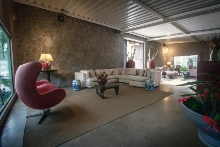 Sala de estar da pousada, com poltronas de design e vista para o jardim